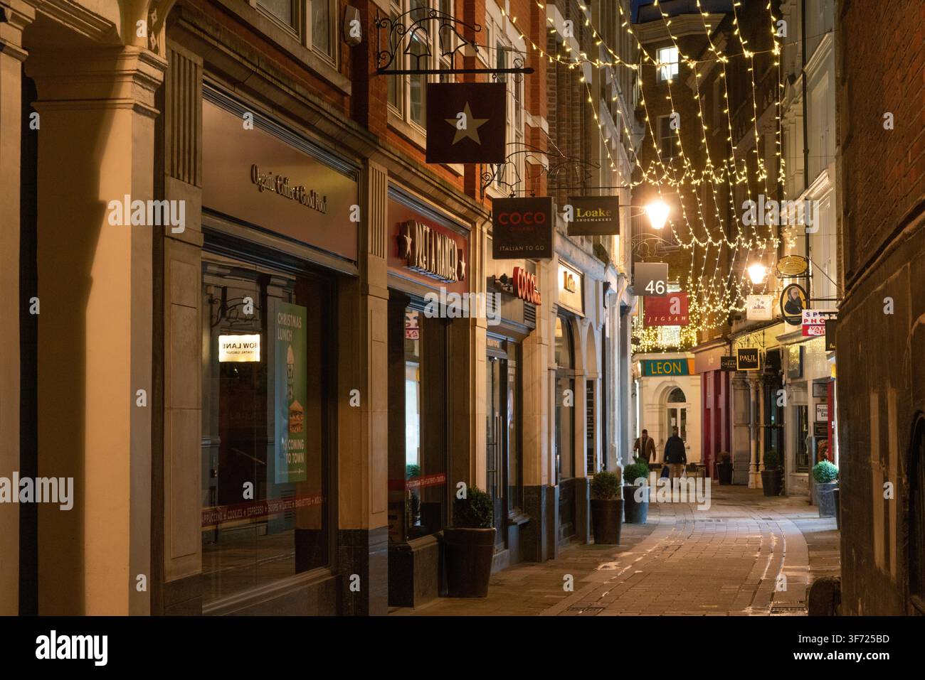 I pedoni passeggiano lungo l'affascinante Bow Lane, illuminato in modo festoso, vicino a Cheapside, nella City di Londra, in una tranquilla serata invernale. Foto Stock