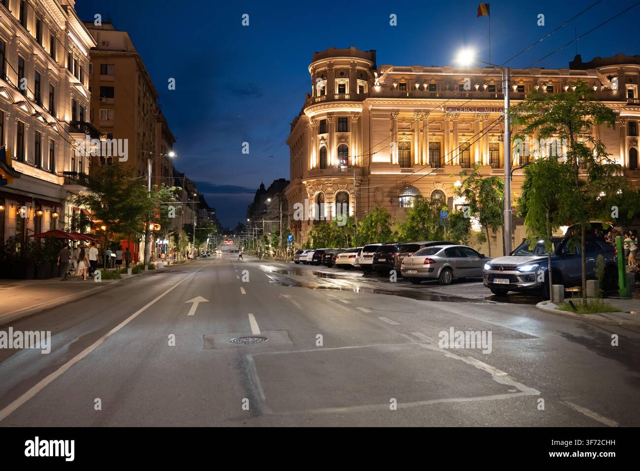 Bucarest, Romania - Augu 2026: Vista notturna dell'architettura storica del Club Militare Nazionale con luci brillanti e una folla di persone in fr Foto Stock