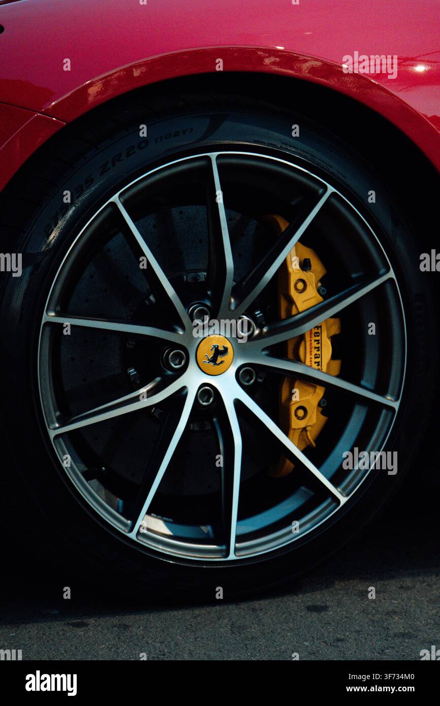 Primo piano di un cerchione in lega di un'auto sportiva di lusso con logo badge Ferrari al centro e pinza dei freni gialla Foto Stock