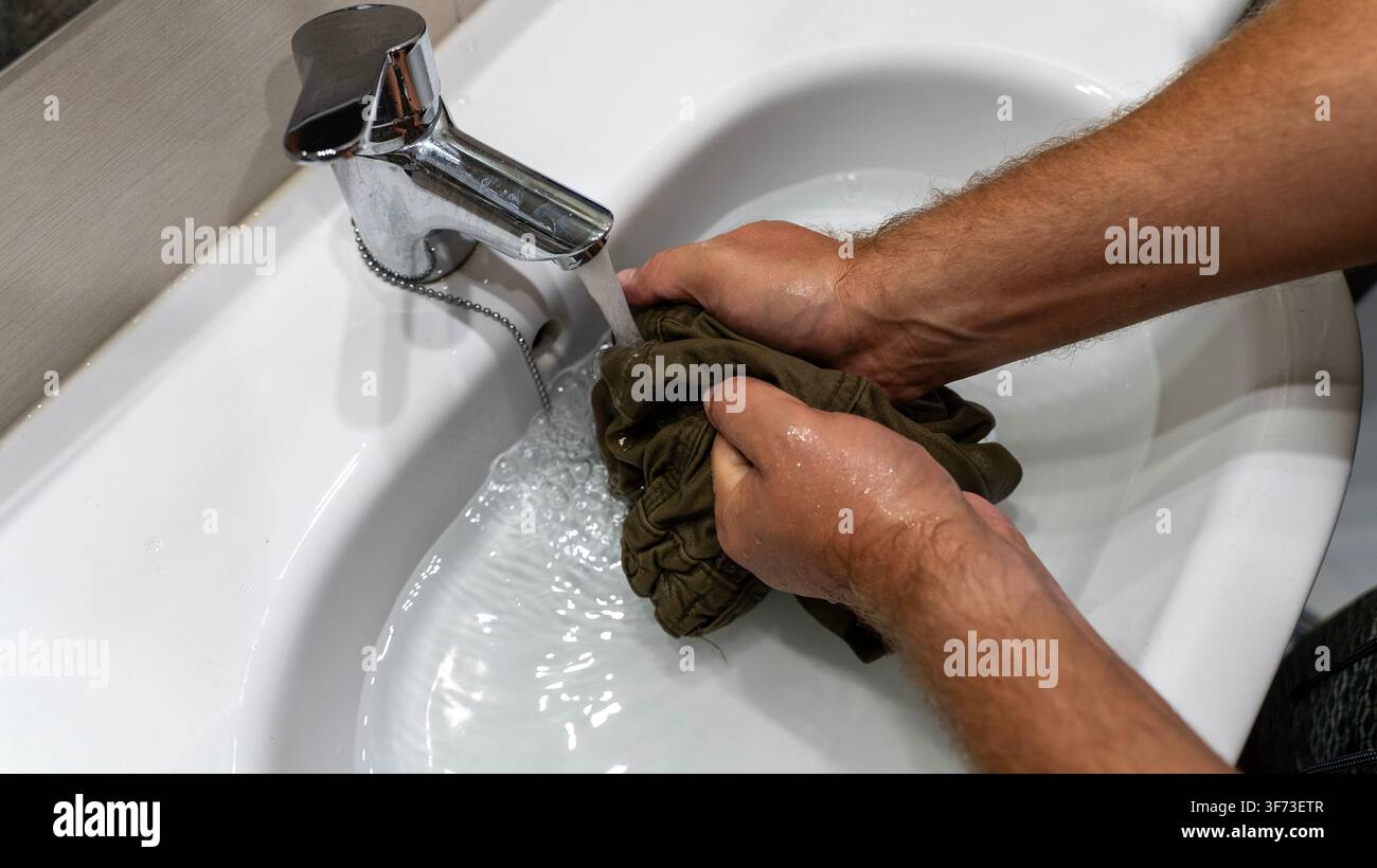 Lavare le mani, vestiti sotto l'acqua corrente nel lavandino del bagno Foto Stock