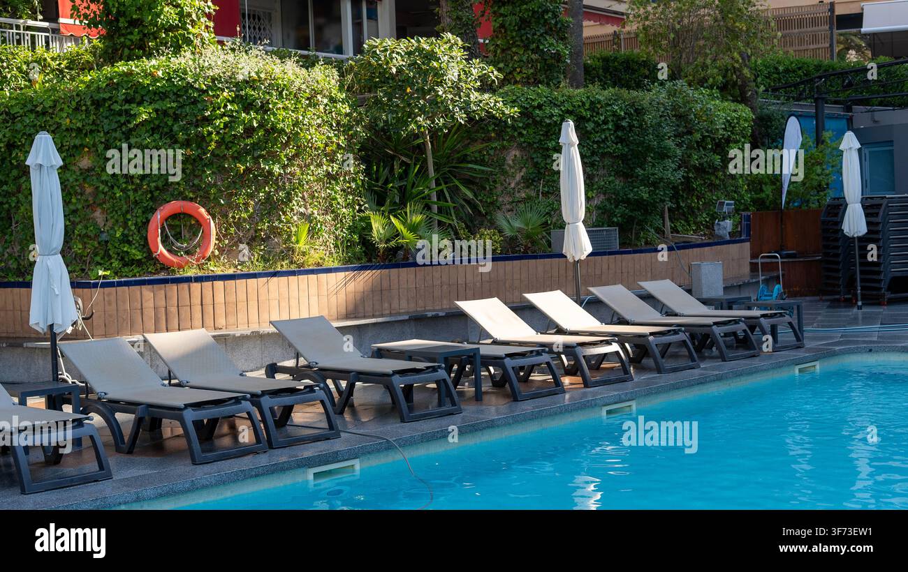 Piscina dell'hotel con sdraio e giardino tropicale Foto Stock