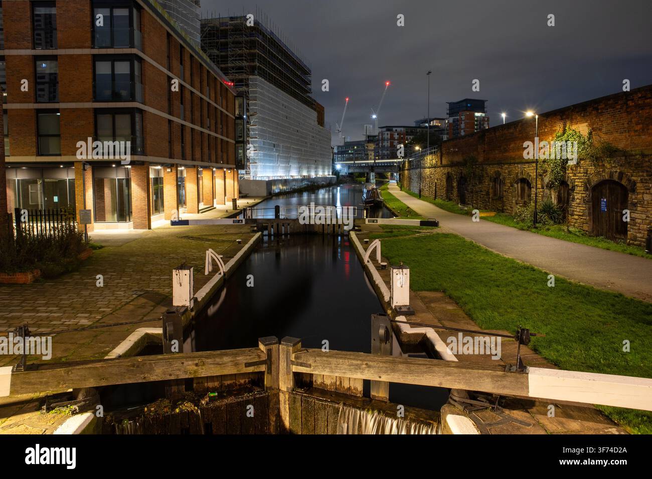 Chiusure illuminate sul canale di Leeds e Liverpool a Leeds, circondate da edifici residenziali moderni Foto Stock