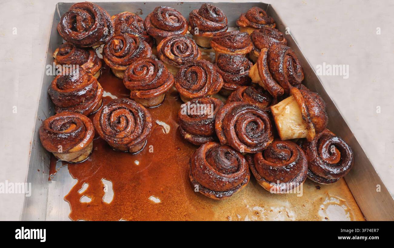 Pasticcini caramellizzati impilati con sciroppo ambrato lucido in un vassoio su una tovaglia bianca a una bancarella del mercato Foto Stock