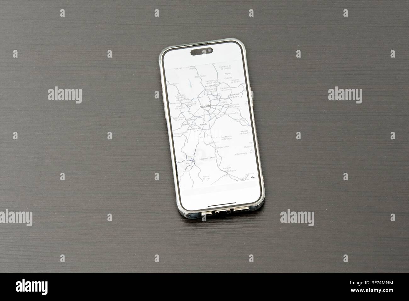 Smartphone che mostra la mappa della regione di Madrid, appoggiato su una superficie di legno scuro Foto Stock