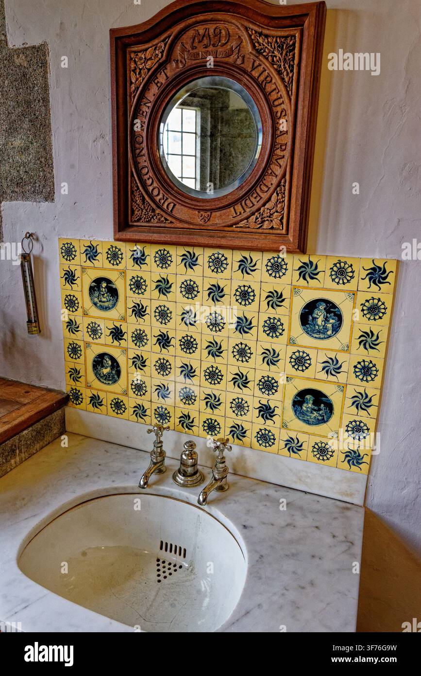 Un elegante lavabo antico in marmo a Castle Drogo, Devon, Inghilterra, scattato il 25.08.2024, con uno sfondo a piastrelle giallo vivace e un ca ornato Foto Stock