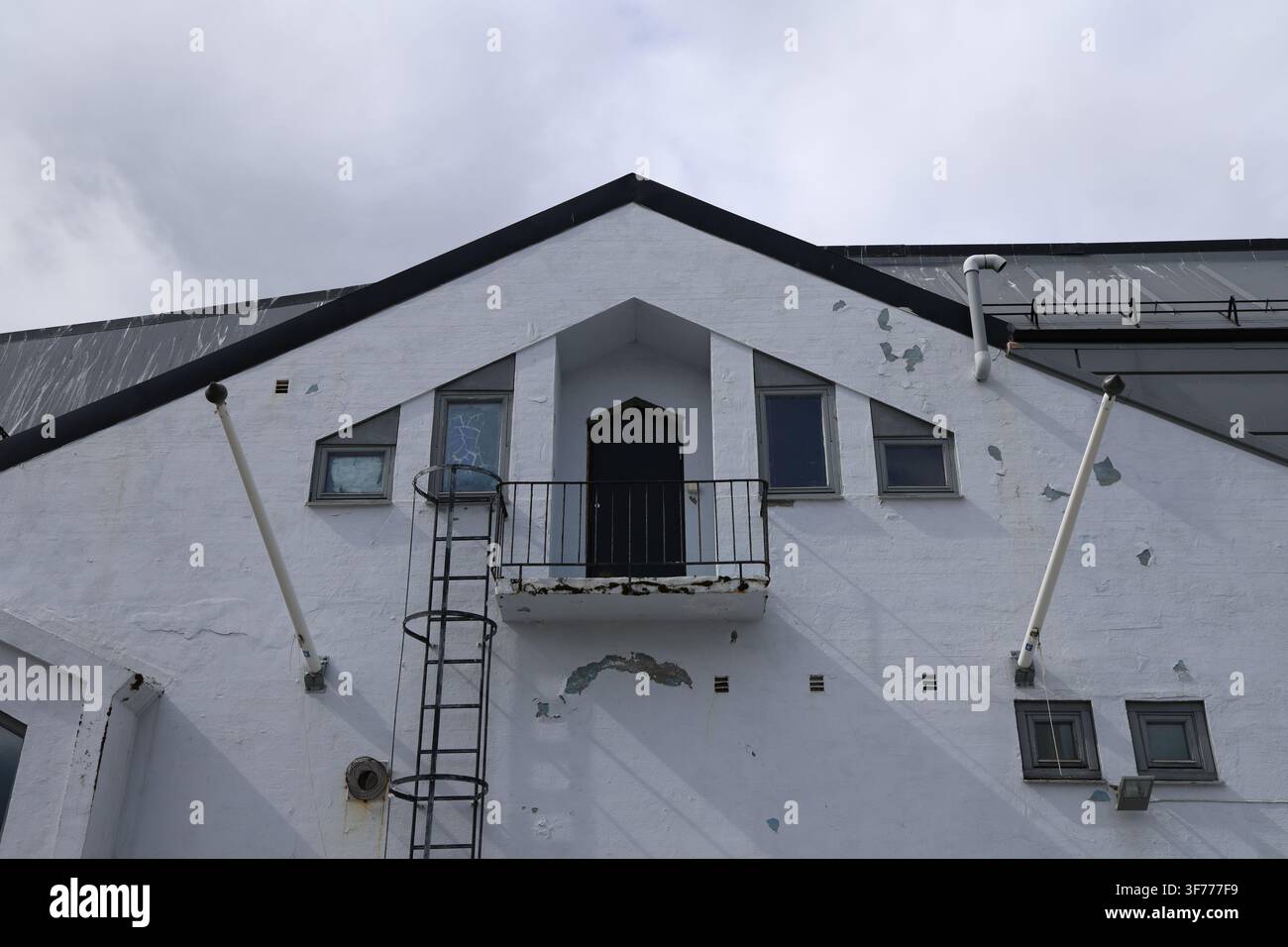 Facciata di edificio bianca erosa con vernice scrostata e segni visibili di invecchiamento. Foto Stock