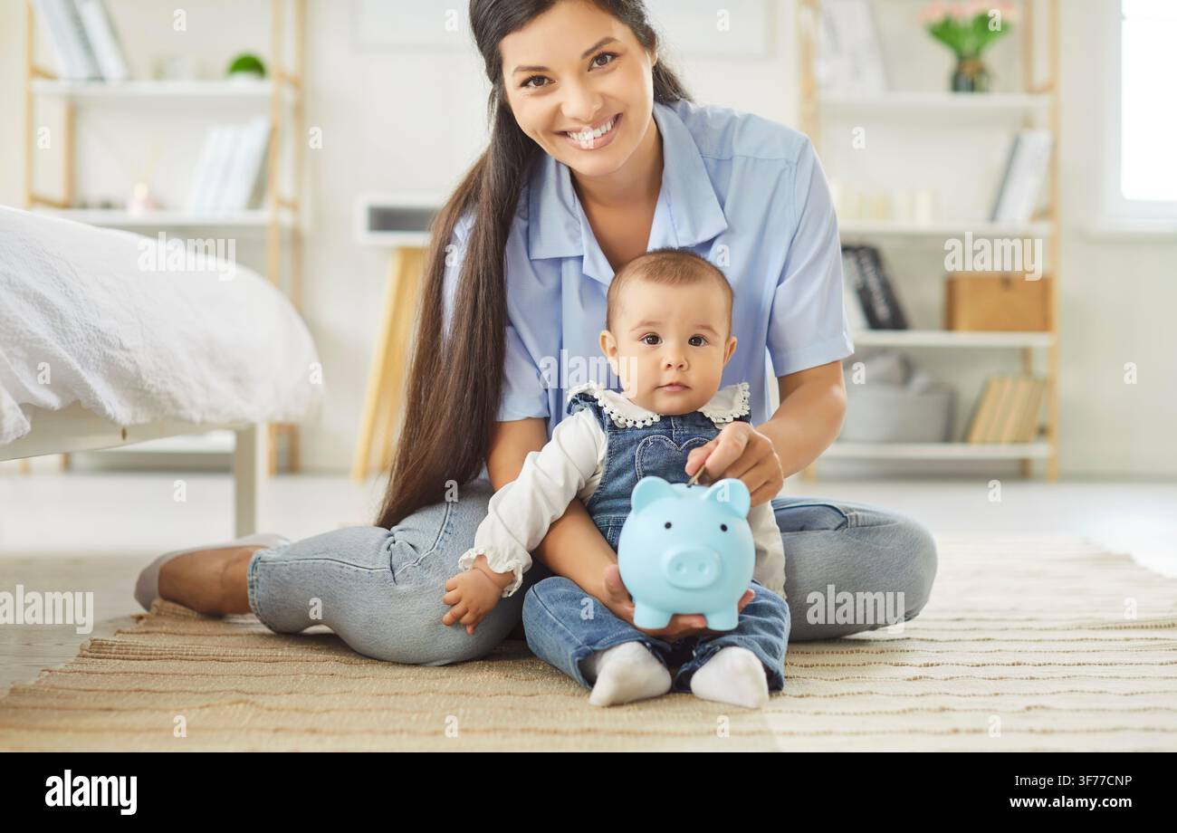 Madre sorridente e bambino che tengono un maialino blu, risparmio e abitudini finanziarie precoci Foto Stock
