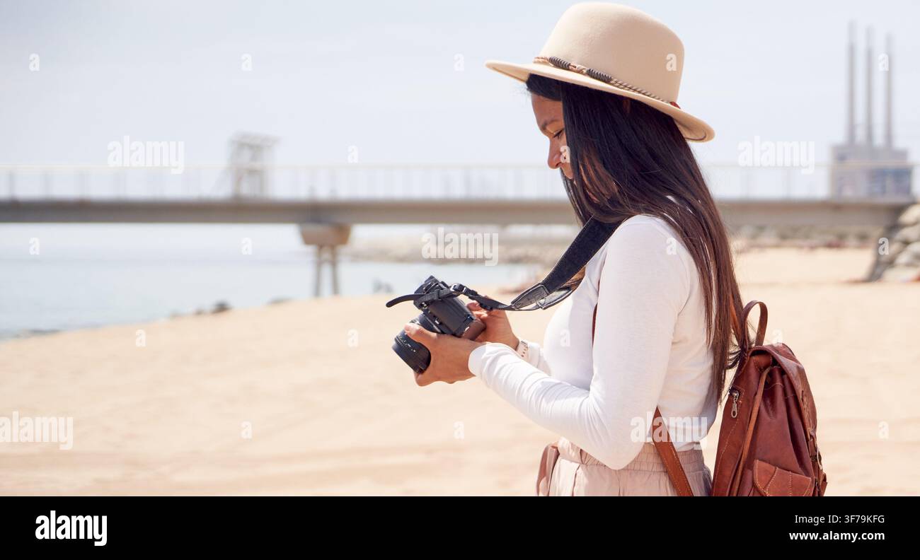 Donna che fotografa la spiaggia con una fotocamera Foto Stock