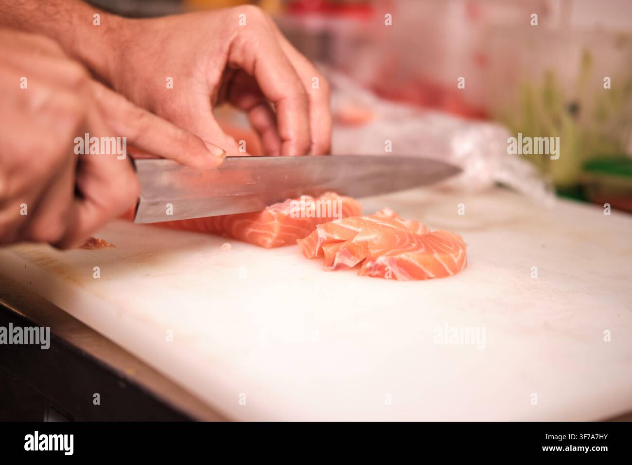 Mani di chef che preparano un filetto di salmone crudo fresco su un tagliere bianco Foto Stock
