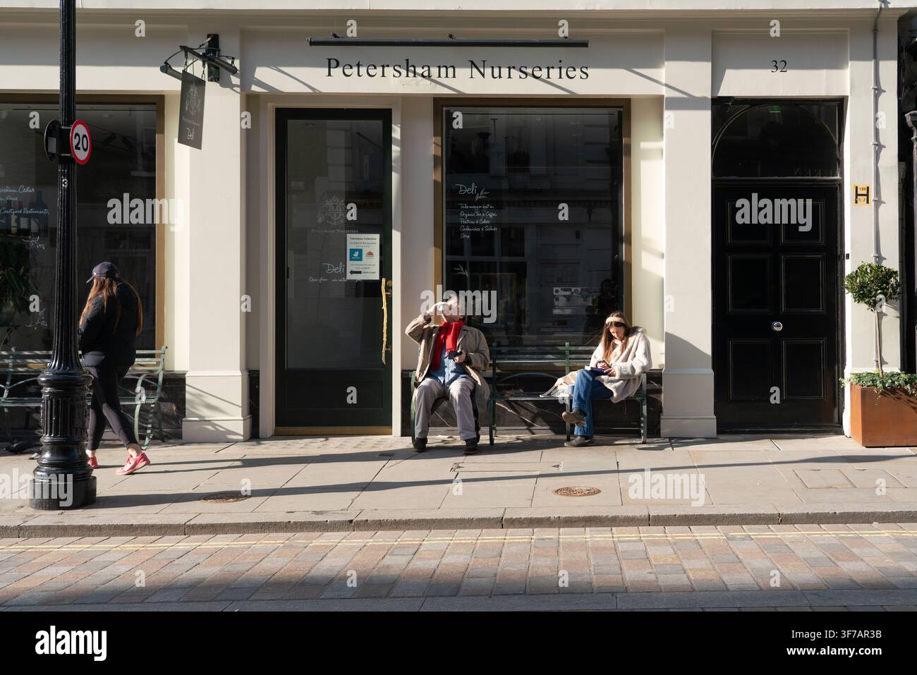 Le persone si rilassano e godono del sole su una panchina fuori dal Petersham Nurseries Deli su King Street a Covent Garden, Londra. Foto Stock