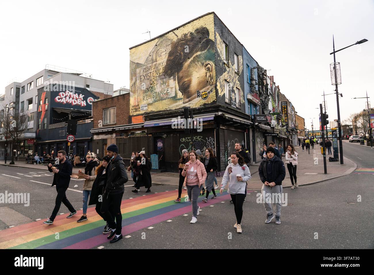 Le persone attraversano il percorso arcobaleno a Camden High St e Jamestown Rd, Londra, sotto il murale di Dr. Martens durante il lockdown COVID-19. Foto Stock