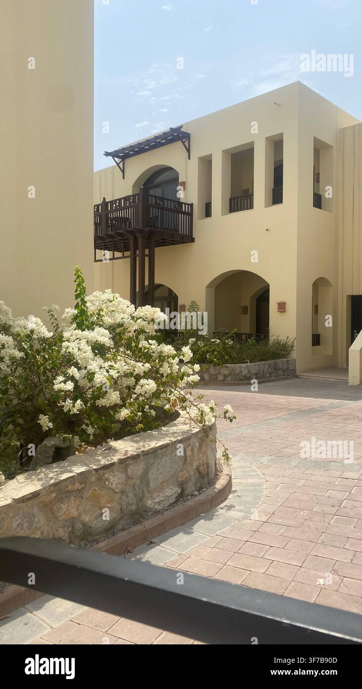Villa tradizionale in stile mediorientale con finestre ad arco e balcone in legno circondata da fiori di bougainvillea bianchi in piena fioritura. Foto Stock