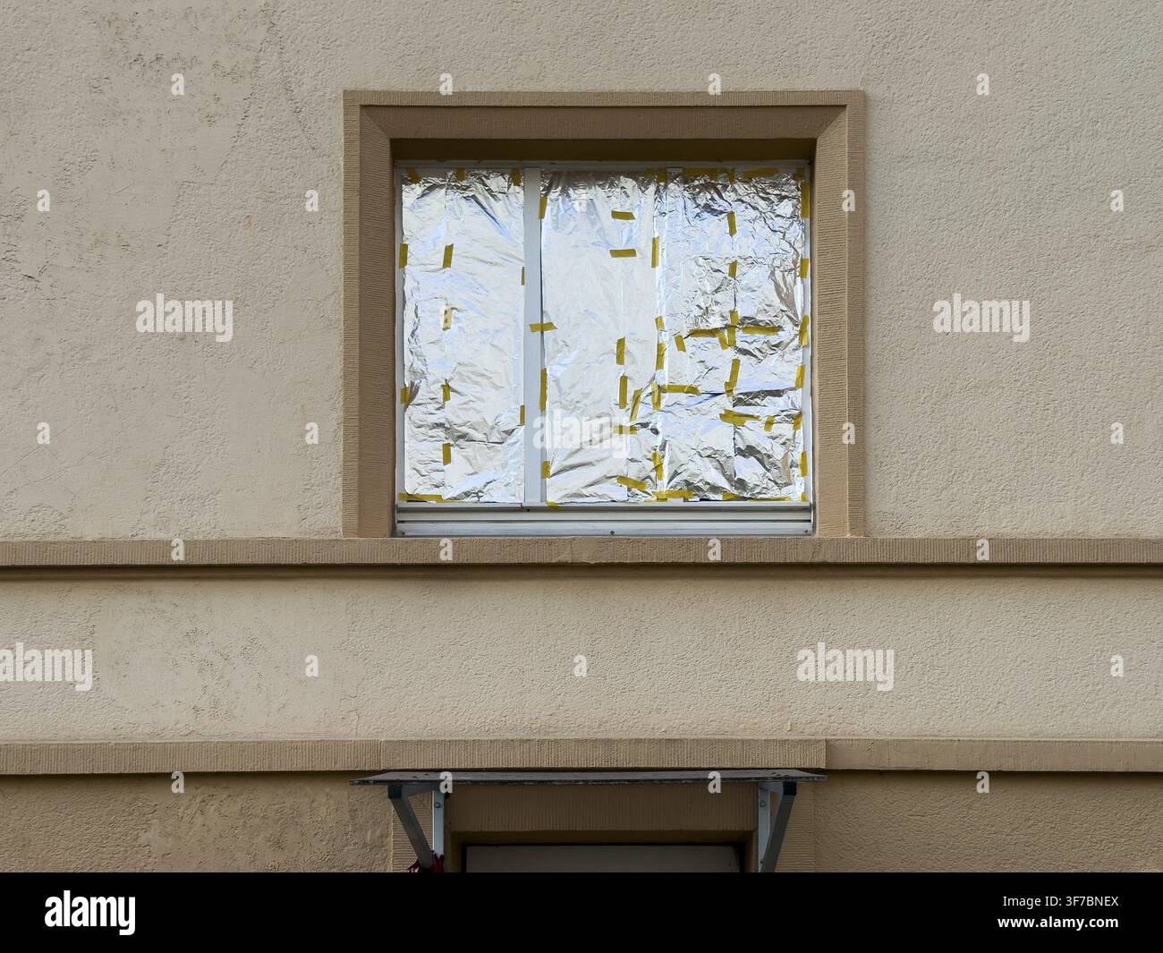 Finestra di una facciata di casa completamente coperta all’interno con foglio di alluminio – protezione solare o schermo per la privacy improvvisato, Wuppertal, Ge Foto Stock