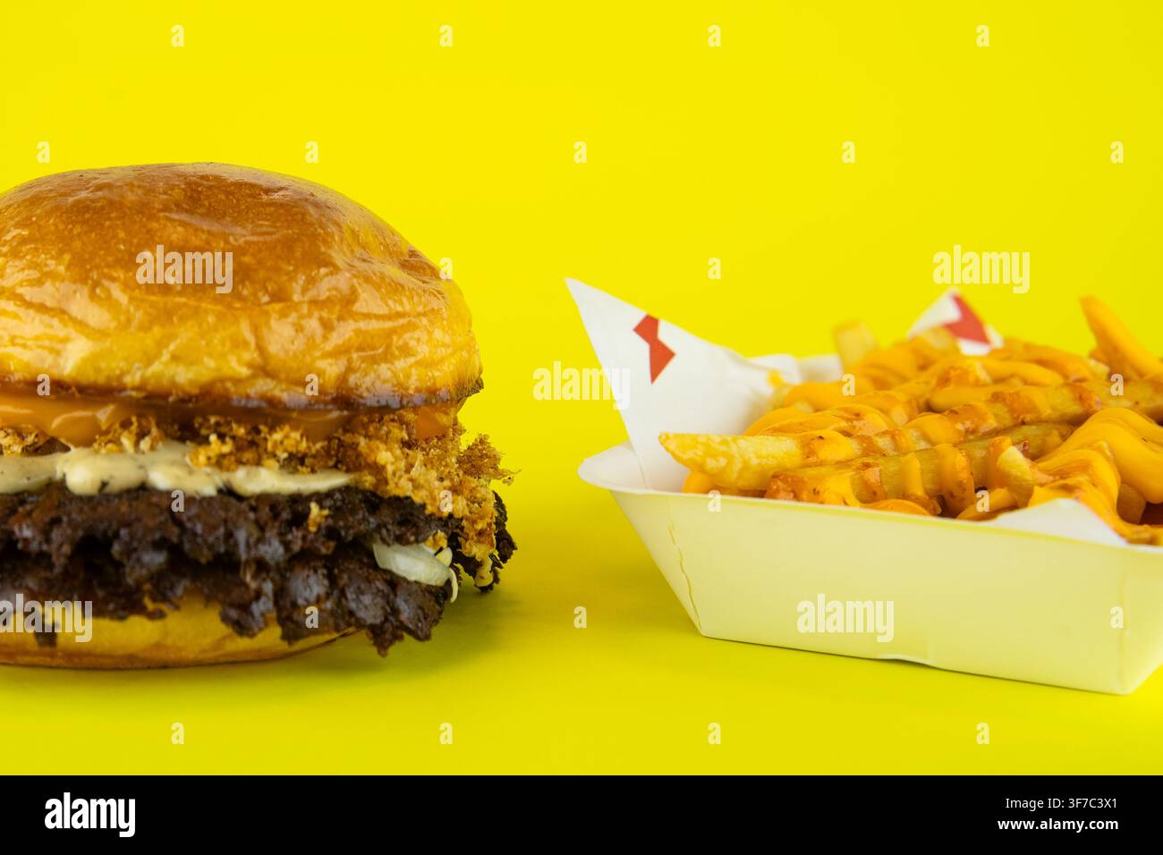 Hamburger smash con doppio patty e patatine a forma di waffle al formaggio che servono un classico pasto fast food Foto Stock