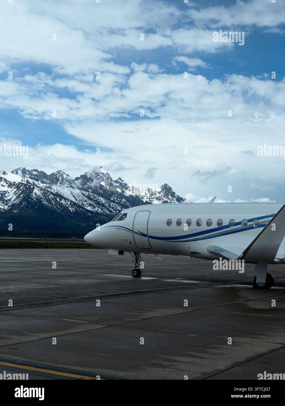 Jet privato sulla rampa con montagne coperte di neve sullo sfondo Foto Stock