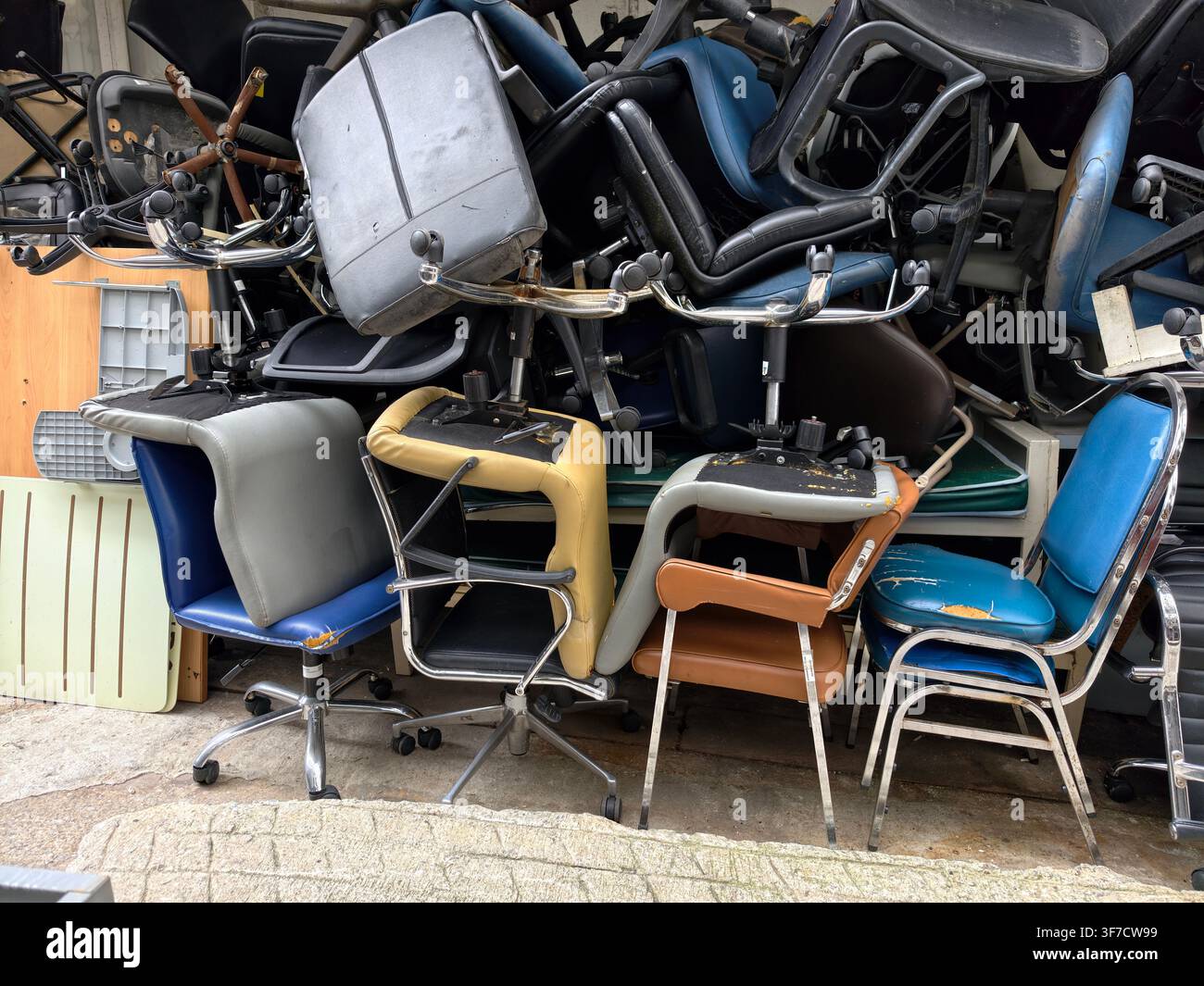 Pila di vecchie sedie da ufficio rotte conservate all'aperto Foto Stock