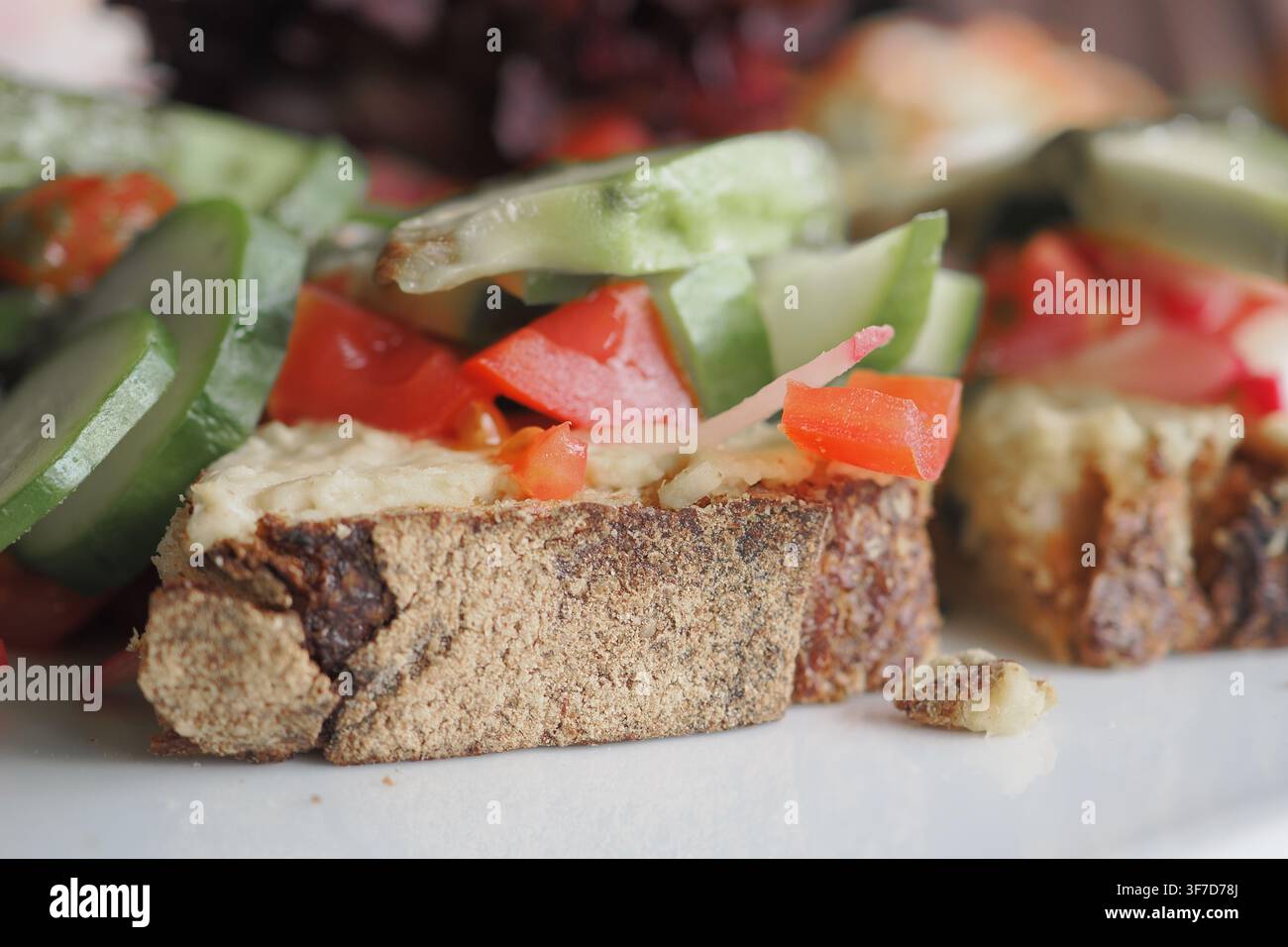 Verdure fresche su pane disposte su un piatto bianco Foto Stock