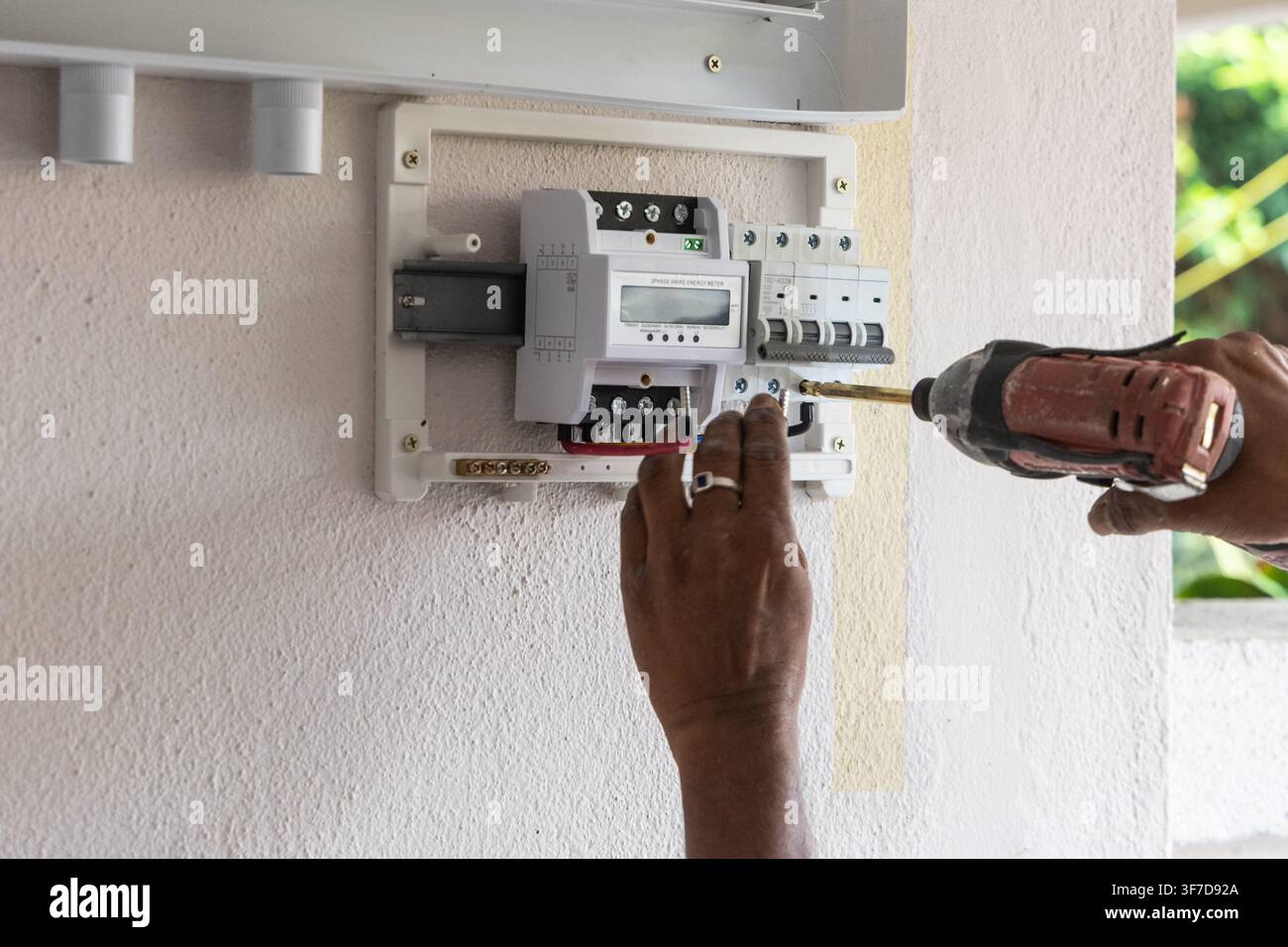 Primo piano di un tecnico che installa un invertitore ibrido fotovoltaico solare in una casa residenziale Foto Stock