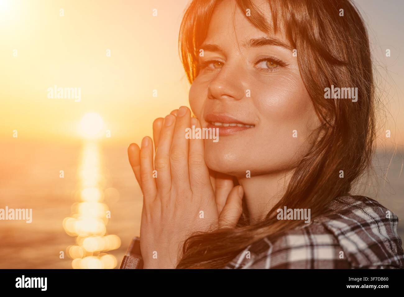 Ritratto di donna sorridente al tramonto sulla calma del mare durante l'ora dorata con un caldo effetto di luce Foto Stock