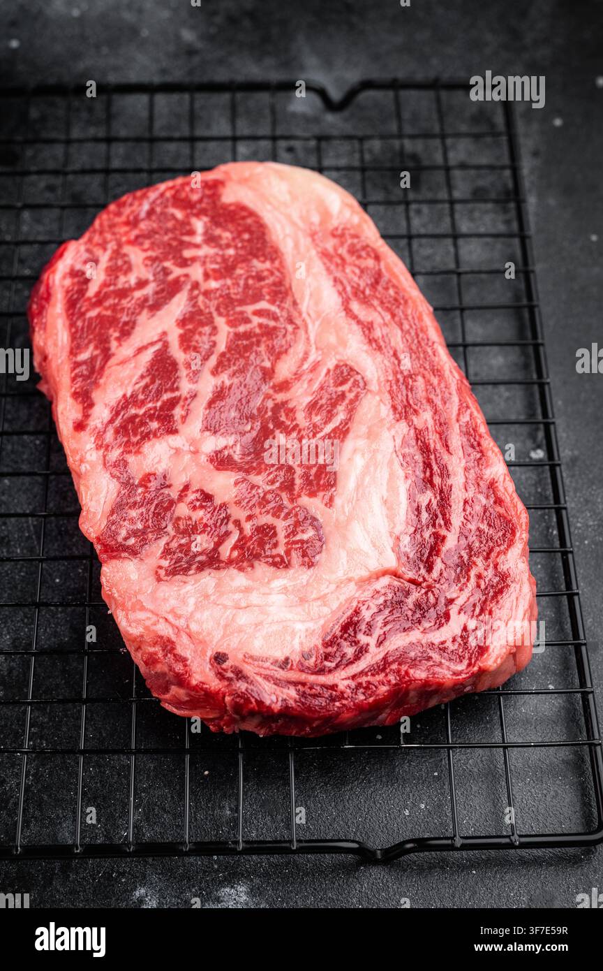 Bistecca cruda di riso nota anche come entrecote scotch o delmonico. Filetto di costolette di manzo marmorizzate tagliate su sfondo nero Foto Stock