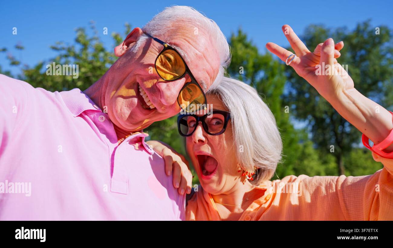 Coppia di anziani che fanno facce buffe e il segno della V Foto Stock