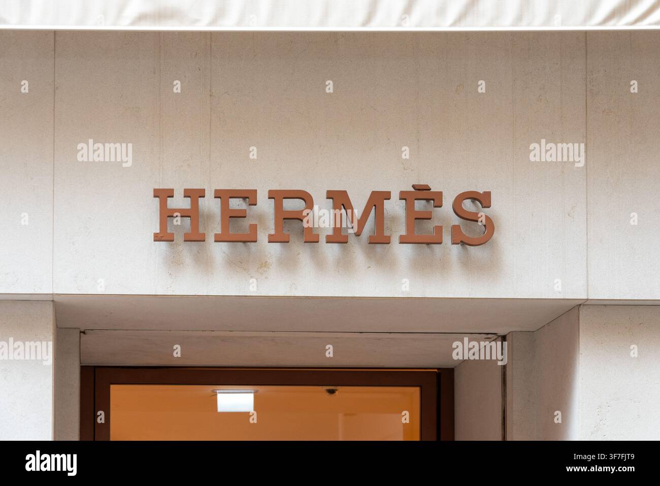 ITALIA, VENEZIA, 11 LUGLIO 2025: L'immagine mostra un'insegna Hermes montata sopra l'ingresso di una boutique su un muro esterno bianco. Foto Stock