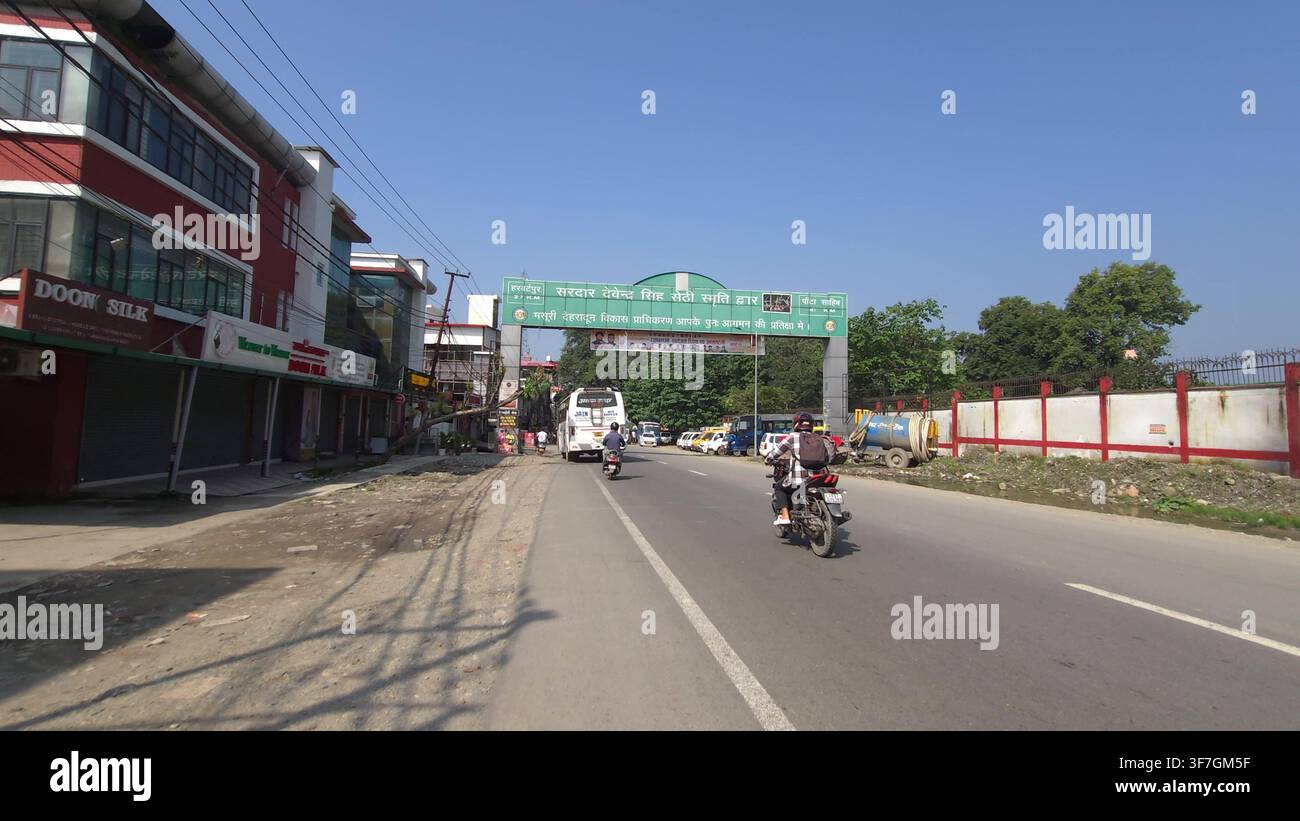 Scena di traffico sull'autostrada con autobus e motociclette che passano sotto un arco di un luogo di interesse Foto Stock