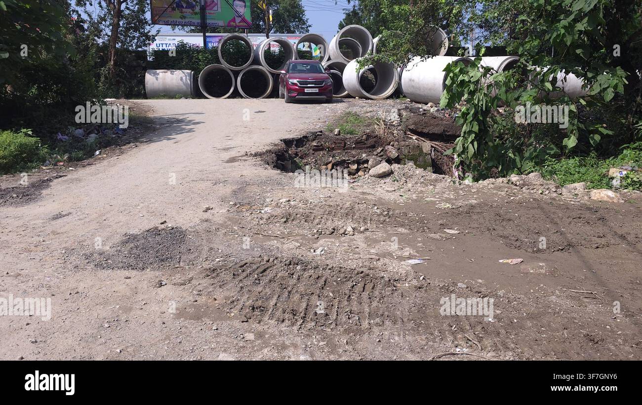 Grandi tubi di cemento impilati su terreno terroso vicino a un'auto e alberi con cemento Foto Stock