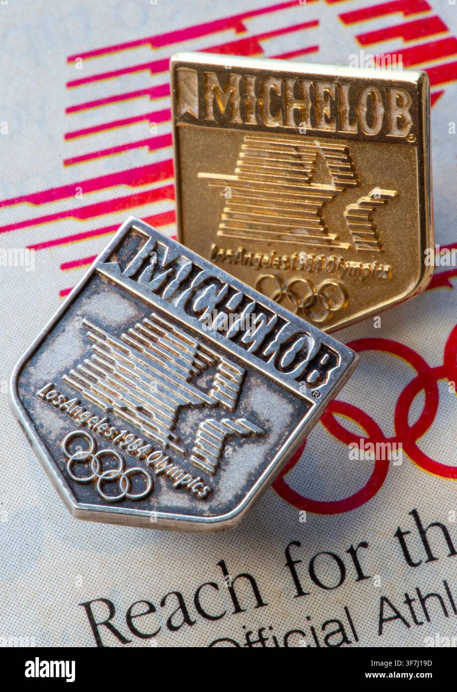 Prima piano di spille da giacca in oro e argento Michelob beer, sponsor ufficiale delle Olimpiadi estive del 1984 a Los Angeles, Stati Uniti Foto Stock