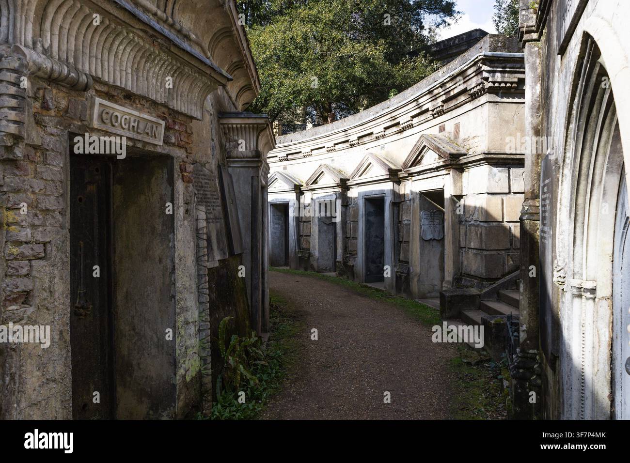 Un sentiero stretto si snoda tra le tombe di pietra erodate del cimitero di Highgate. Famoso cimitero vittoriano a Londra, UK, con architettura gotica. Foto Stock