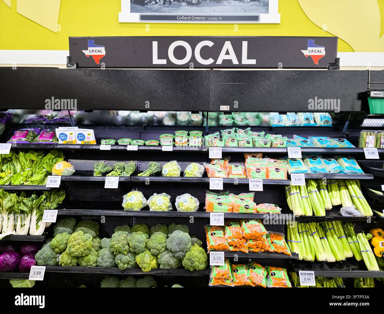 ADDISSON, TX, USA - 21 LUGLIO 2026: Una vetrina di ortaggi freschi etichettati come prodotti locali in un negozio di alimentari. La sezione include broccoli, sedano, s Foto Stock