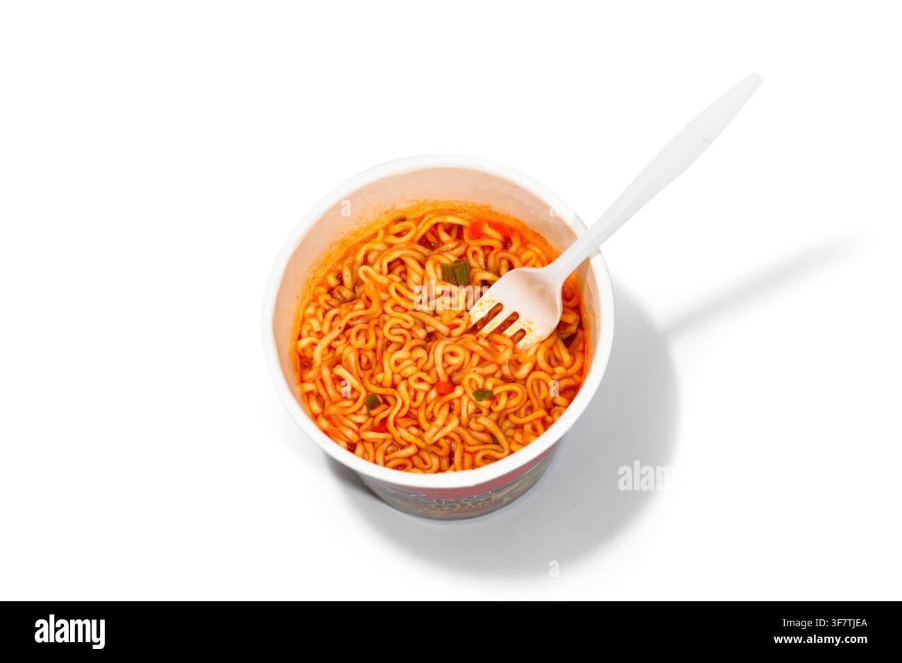 Una tazza di noodles istantanei ramen. Una ciotola di ramyun Nongshim Shin cotto con un ritaglio di forchetta di plastica su sfondo bianco Foto Stock