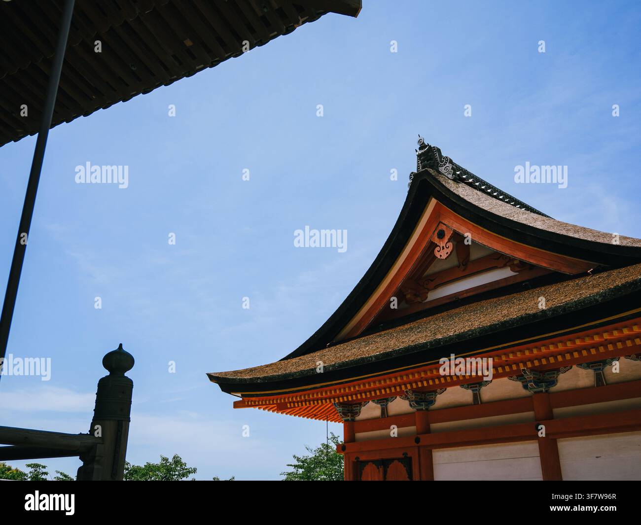 Tetto tradizionale di un tempio giapponese con dettagli in legno ornati contro un cielo blu limpido a Kyoto, Giappone Foto Stock