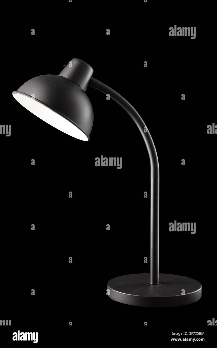 Moderna lampada da scrivania nera accesa isolata su sfondo nero, verticale Foto Stock