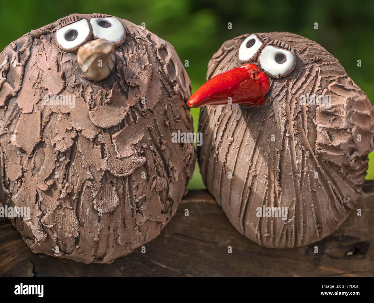 Coppia di uccelli scolpiti in ceramica stravaganti come decorazione da giardino con becchi in argilla marrone strutturata Foto Stock