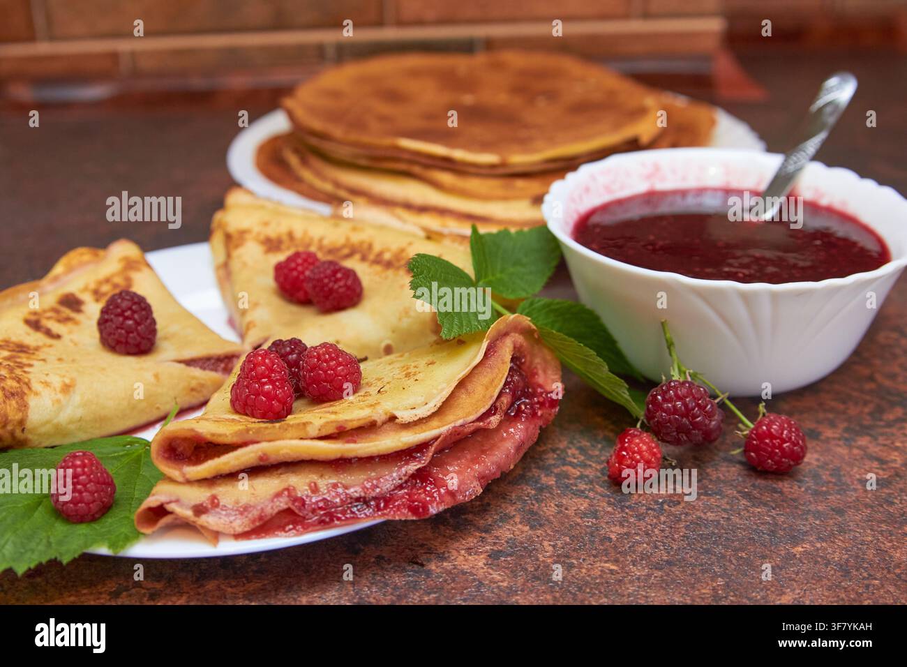 deliziosi pancake succosi con marmellata di lamponi sul tavolo in cucina Foto Stock
