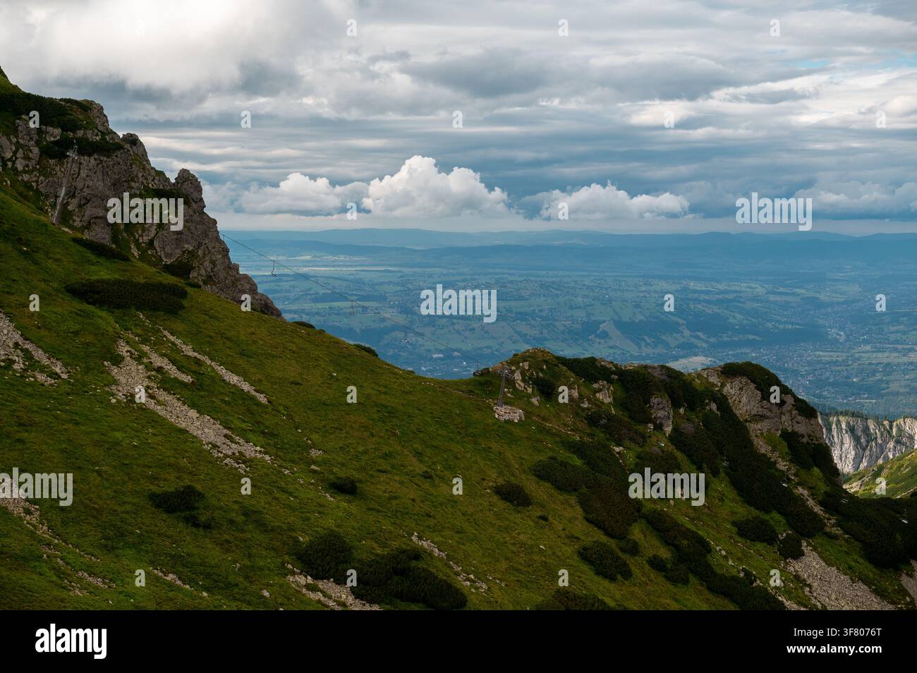 Cresta montuosa erbosa che si affaccia sulla valle in una giornata nuvolosa Foto Stock