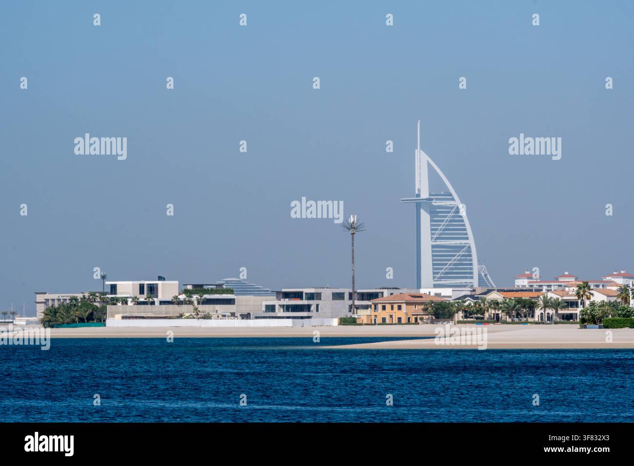L'hotel Burj Al Arab è visibile da lontano dietro le costruzioni costiere e l'acqua blu, ripreso il 22 maggio 2024 a Dubai, Emirati Arabi Uniti Foto Stock