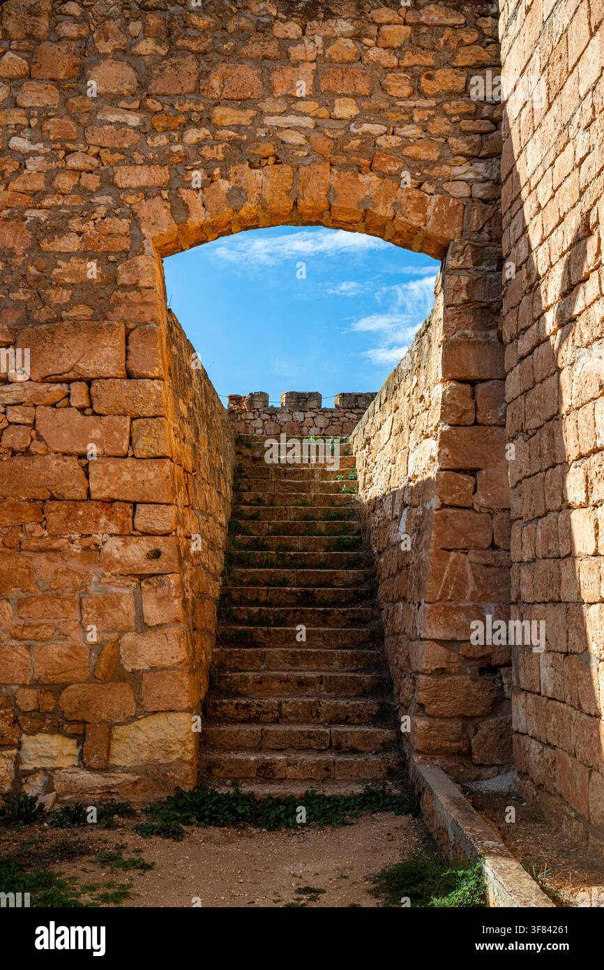 Esplorazione dell'arco di pietra e dei gradini di un antico forte a Qasr Libya con sfondo di cielo azzurro nella Libia orientale Foto Stock