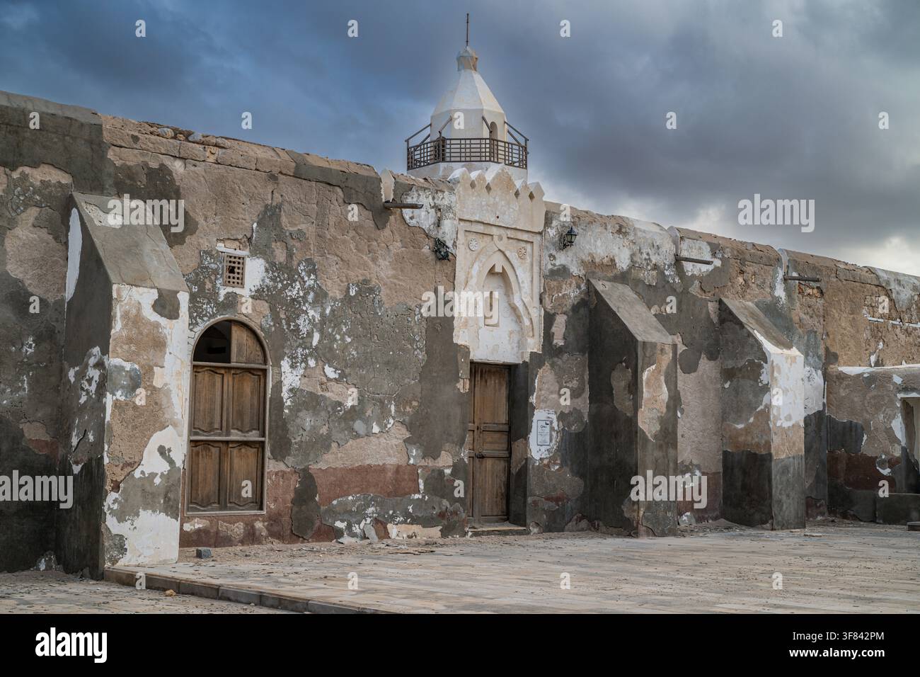 Sito storico sull'isola di Suakin mostra architettura in corallo e vecchie mura sotto un cielo drammatico nel Sudan Foto Stock