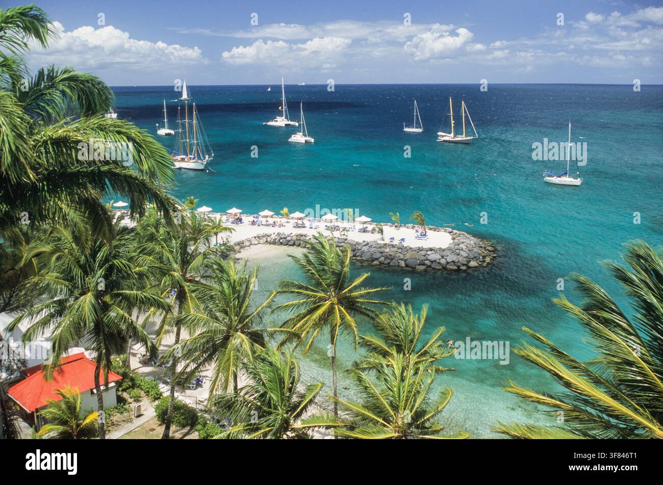 Barche a vela ormeggiate in acque turchesi vicino a una spiaggia sabbiosa a Les Trois-Ilets, isola della Martinica, in un pomeriggio soleggiato Foto Stock
