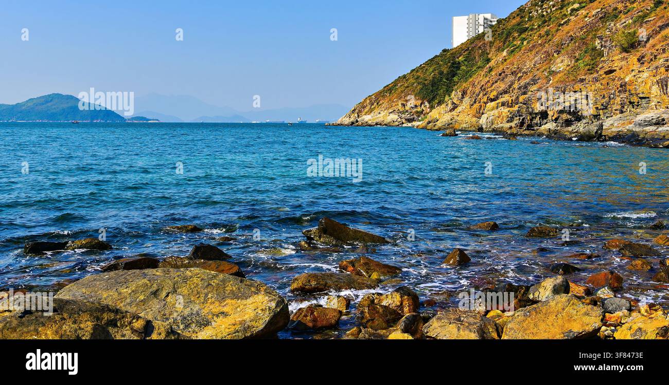 Rocce e collina sul mare vicino al Monte Johnston ad Ap Lei Chau, Hong Kong catturano il paesaggio costiero e le acque azzurre limpide Foto Stock