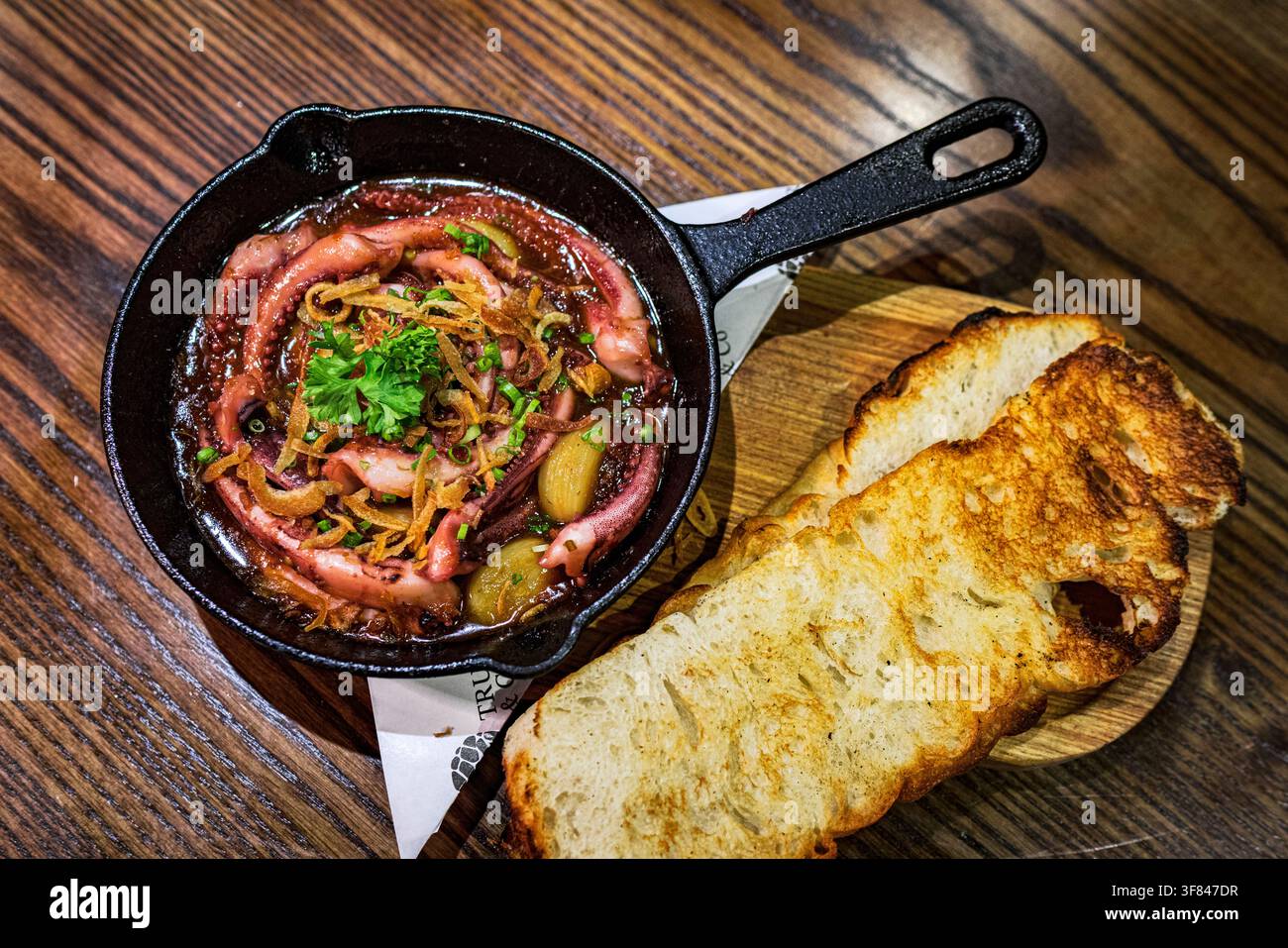 Polpo in salsa piccante servito con pane tostato per un pasto di frutti di mare in Vietnam Foto Stock