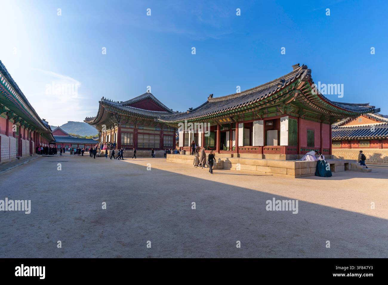 I visitatori esplorano il palazzo di Gyeongbokgung sotto il sole splendente a Seoul, in Corea del Sud, durante una giornata calda Foto Stock