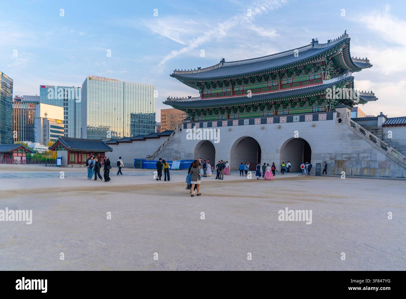 Persone che camminano vicino al Portale Gwanghwamun mentre il sole tramonta sul Palazzo Gyeongbokgung a Seoul, in Corea del Sud Foto Stock