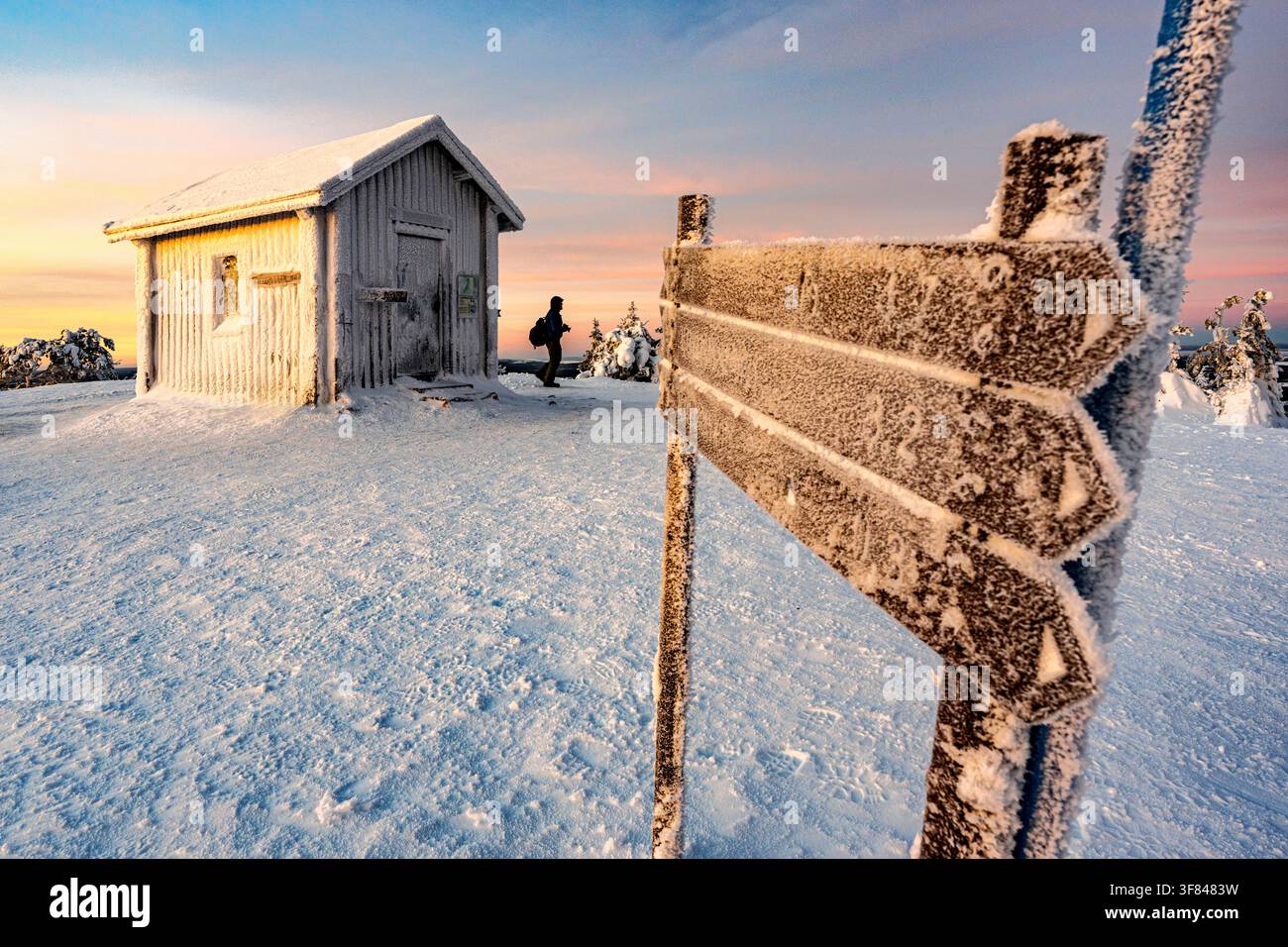 Uomo che fa escursioni vicino a un rifugio alpino e segnali di sentiero in inverno, Ruka, Kuusamo, Lapponia, Finlandia Foto Stock