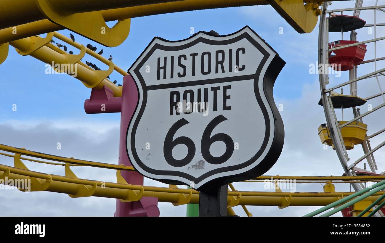 Insegna storica della Route 66 nel parco divertimenti di Santa Monica, California con un cielo blu limpido sullo sfondo Foto Stock