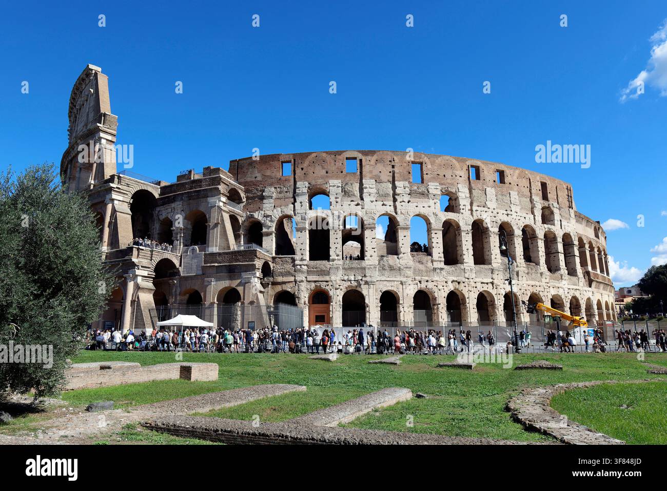 Enorme struttura ellittica del Colosseo attira visitatori a Roma in una giornata soleggiata Foto Stock