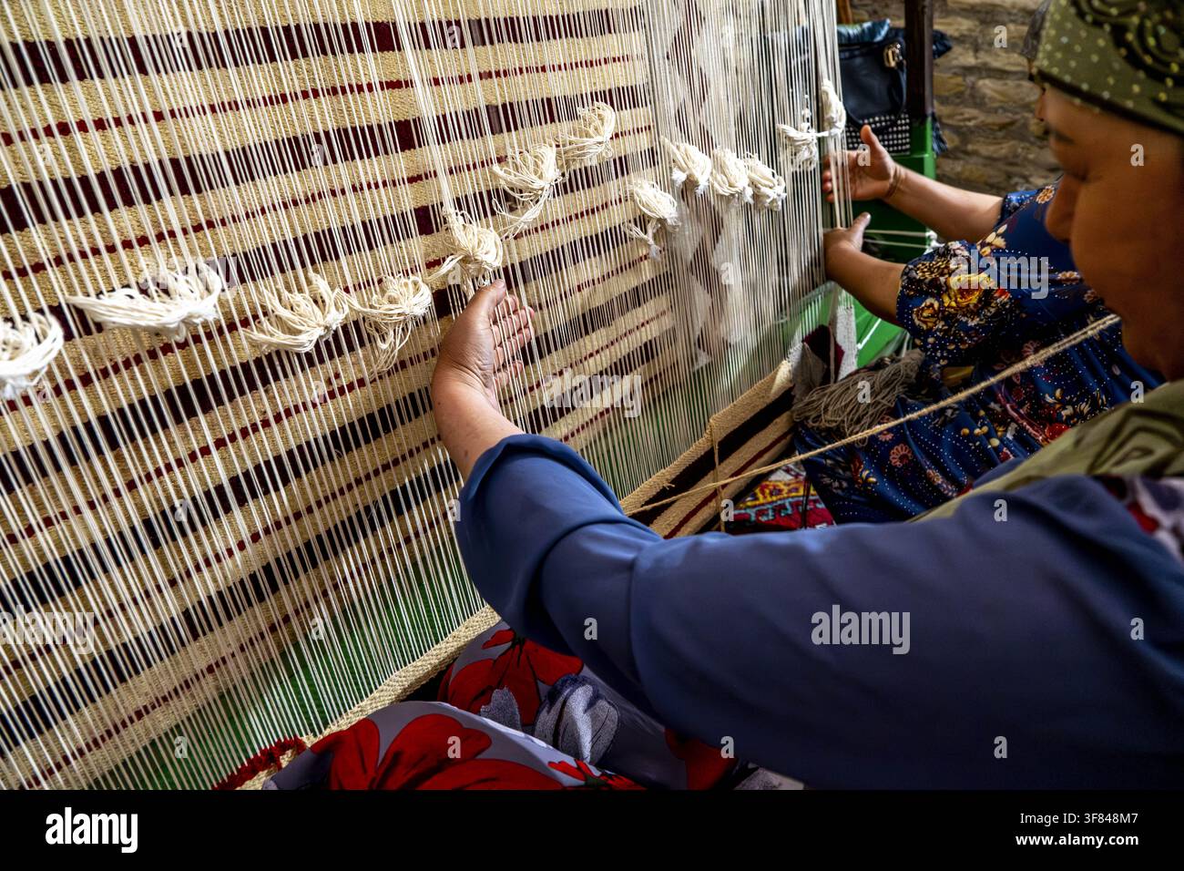 Produzione di tappeti in una bottega a Itchan Kala, vecchia città di Khiva, Uzbekistan, con artigiani che tessono disegni e motivi tradizionali Foto Stock