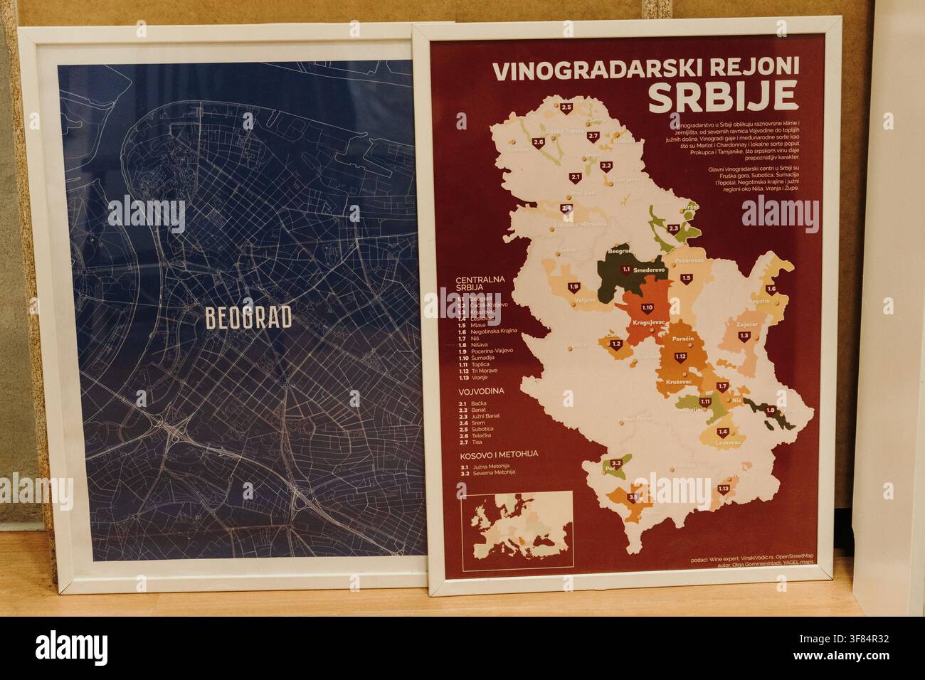 Belgrado, Serbia – 18 luglio 2026. Mappa incorniciata di Belgrado esposta insieme a una mappa illustrata delle regioni vinicole serbe all’interno di un caffè moderno. Foto Stock
